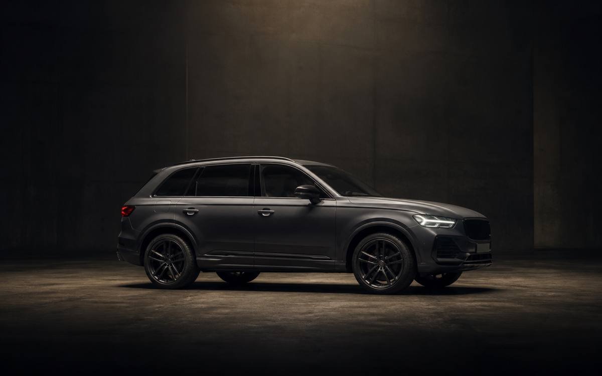 A dark grey luxury SUV lit in a concrete hall